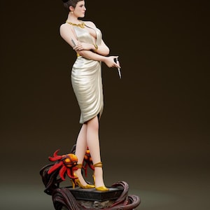 Può includere: Statuetta dettagliata di una donna in abito bianco, gioielli dorati e tacchi gialli. La figura è in piedi su una base con tentacoli rossi e arancioni. La donna tiene in mano una penna e una sigaretta.