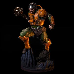以下が含まれることがあります： ダイナミックなポーズの戦士の精巧なアクションフィギュア。フィギュアは緑と金の鎧を身につけ、黒いヘルメットと武器を持っています。フィギュアは黒い背景に対して岩の台座に立っています。