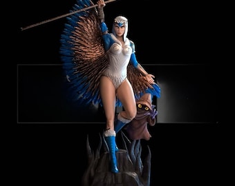 May include: A statue of a female character in a white and blue bodysuit with feathered wings, holding a staff with a crescent moon on top. A small, brown creature stands beside her. The statue is on a dark, textured base.