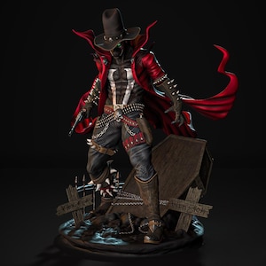 May include: A detailed figurine of a character in a black hat and red cape, holding a gun. The figure has a white chest emblem and is standing on a base with a tombstone and wooden cross. The figure is wearing black pants and boots.