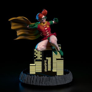 May include: A figurine of Robin in a dynamic pose, leaping above a stylized cityscape. The figure wears a red and green costume with a yellow cape and green-tinted glasses. The base is a dark, rocky platform.