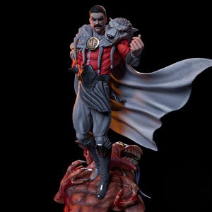 May include: A detailed figurine of a character in a red and grey outfit, with a wolf head shoulder piece and a flowing cape. The figure stands atop a monster with a menacing expression. The character has a moustache and is making a hand gesture.