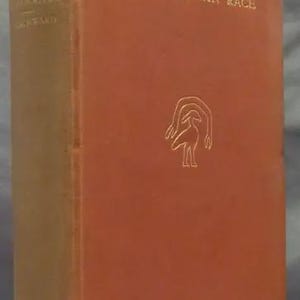May include: A vintage book titled "Origin and Evolution of the Human Race" by Dr. Albert Churchward. The book has a reddish-brown cover with gold lettering and a stylized illustration. The spine is a lighter tan color.