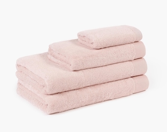 Può includere: Una pila di quattro asciugamani da bagno rosa chiaro. Gli asciugamani sono piegati e hanno una consistenza morbida e soffice. Gli asciugamani sono di colore rosa pallido e sono su uno sfondo bianco. Ideale per il bagno.