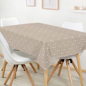 May include: A beige rectangular tablecloth with a geometric pattern of white lines and dots covers a table. The tablecloth is draped over a table with four white chairs with wooden legs.