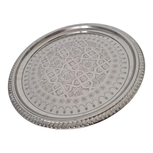 Op de afbeelding: Een zilverkleurige, ovale serveerschaal met een ingewikkeld bloemen- en geometrisch patroon. De schaal heeft een decoratieve, touwachtige rand.
