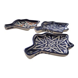 Op de afbeelding: Drie keramische serveerschalen met een unieke vorm en ingewikkelde blauw-witte patronen. De schalen hebben een donkerblauwe rand en bodem, met de tekst "FES & LS" aan de zijkant. De ontwerpen omvatten geometrische en abstracte motieven.