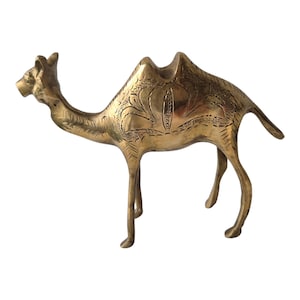 May include: A brass camel figurine with intricate etched floral patterns. The camel is depicted standing, with its head raised. The figurine is a warm gold colour and features detailed design. A decorative item.