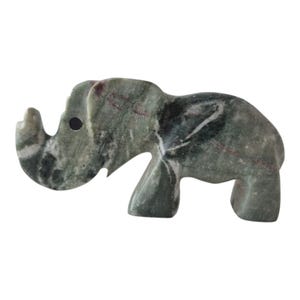 May include: A carved stone elephant figurine in shades of green, gray, and hints of red. The elephant has a trunk, tusks, and large ears. The figurine is a decorative item, likely for display.