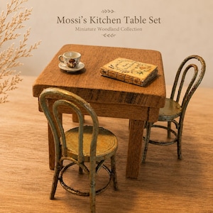 Könnte beinhalten: Ein Miniatur-Küchentisch-Set mit der Aufschrift Mossi's Kitchen Table Set Miniature Woodland Collection. Das Set besteht aus einem quadratischen Holztisch, zwei abgenutzten hellblauen Stühlen, einer kleinen Tasse auf Untertasse und einem Buch.