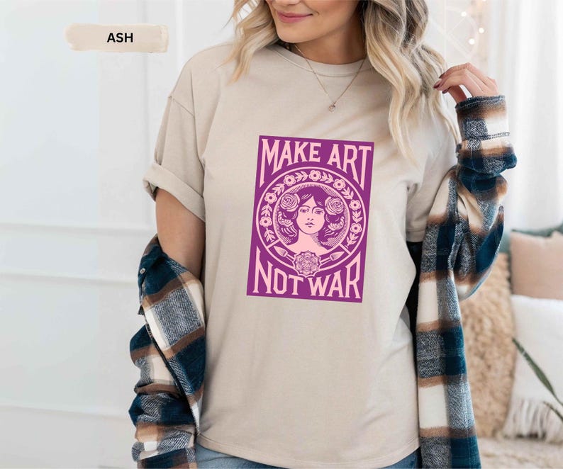以下が含まれることがあります： 「MAKE ART NOT WAR」と書かれた紫色のグラフィックが特徴の、アッシュカラーのTシャツ。 グラフィックは、花の要素に囲まれた女性の顔が特徴です。 ゆったりとしたフィット感のシャツです。
