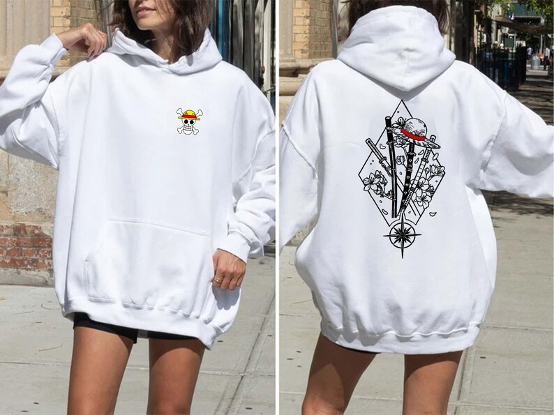 May include: White hoodie with a front pocket and a hood. The front features a small, colorful skull and crossbones logo with a yellow hat. The back displays a black and white graphic of a hat, swords, and flowers within a diamond shape.