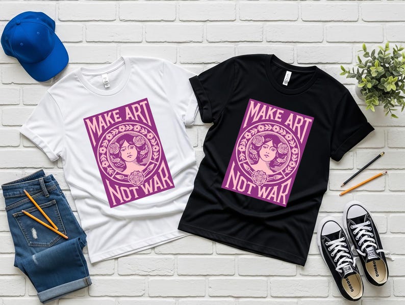 以下が含まれることがあります： 白と黒の2枚のTシャツ。紫色のグラフィックで「MAKE ART NOT WAR」と書かれています。女性の顔と花の要素が描かれています。青い野球帽、ジーンズ、スニーカーも写っています。