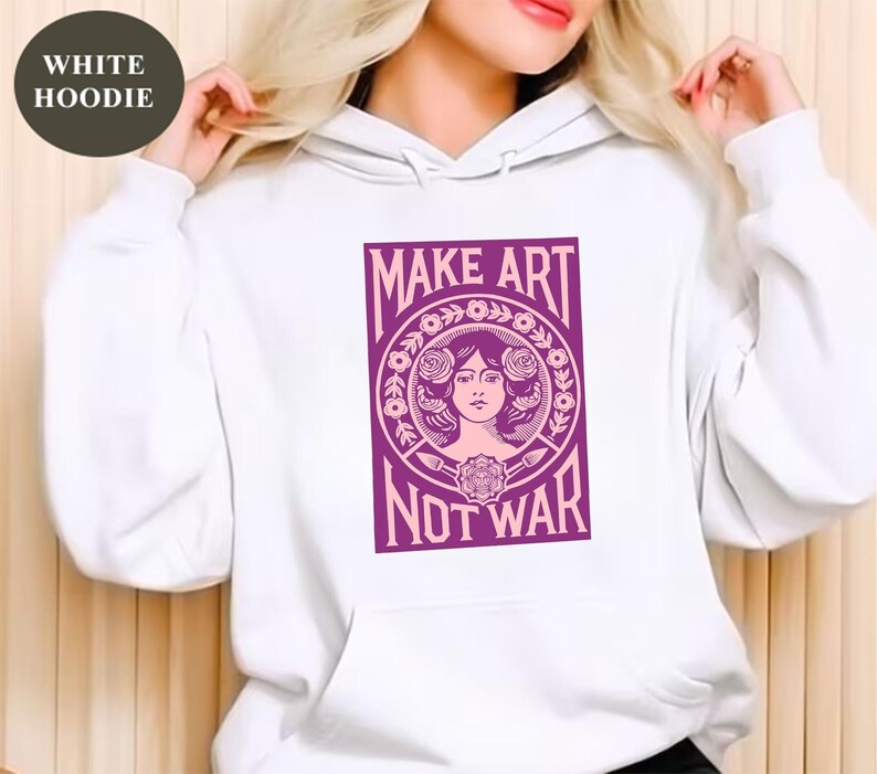 以下が含まれることがあります： 「MAKE ART NOT WAR」と書かれた紫色のグラフィックが特徴の白いパーカー。グラフィックは、花の要素に囲まれた女性の顔が特徴です。パーカーには、ドローストリングフードとフロントポケットが付いています。