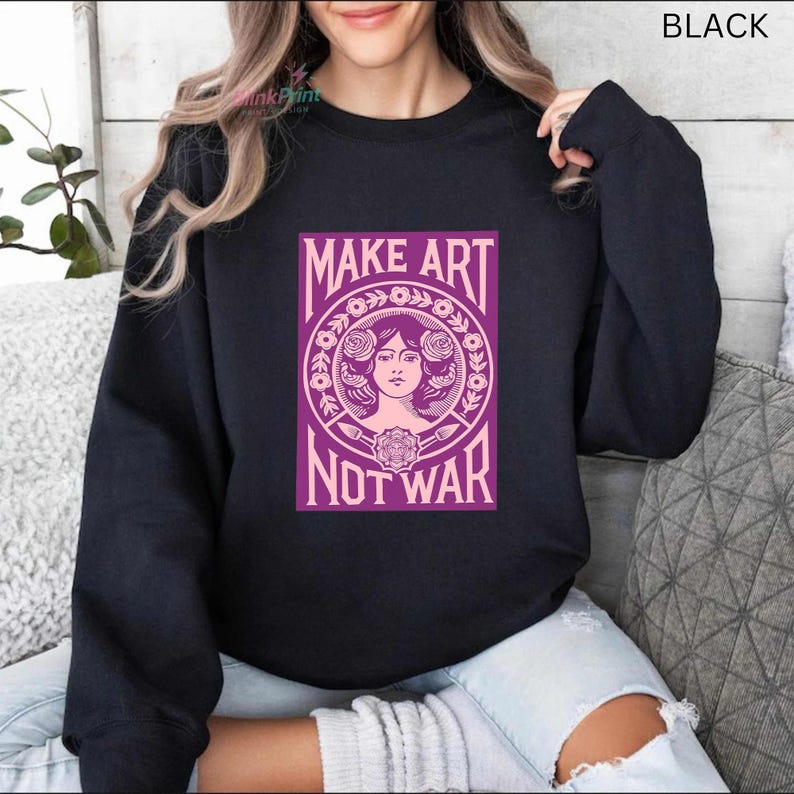 以下が含まれることがあります： 「MAKE ART NOT WAR」と書かれた紫色のグラフィックが特徴の黒いスウェットシャツ。 グラフィックは、花の要素に囲まれた女性の顔を特徴としています。 テキストは大胆で様式化されたフォントです。