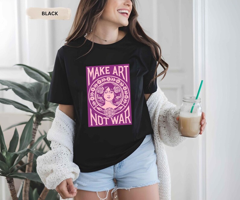 以下が含まれることがあります： 「MAKE ART NOT WAR」と書かれた紫とピンクのグラフィックが特徴の黒いTシャツ。グラフィックは、花の要素に囲まれた女性の顔が特徴です。このシャツは、青いデニムショーツと組み合わせています。