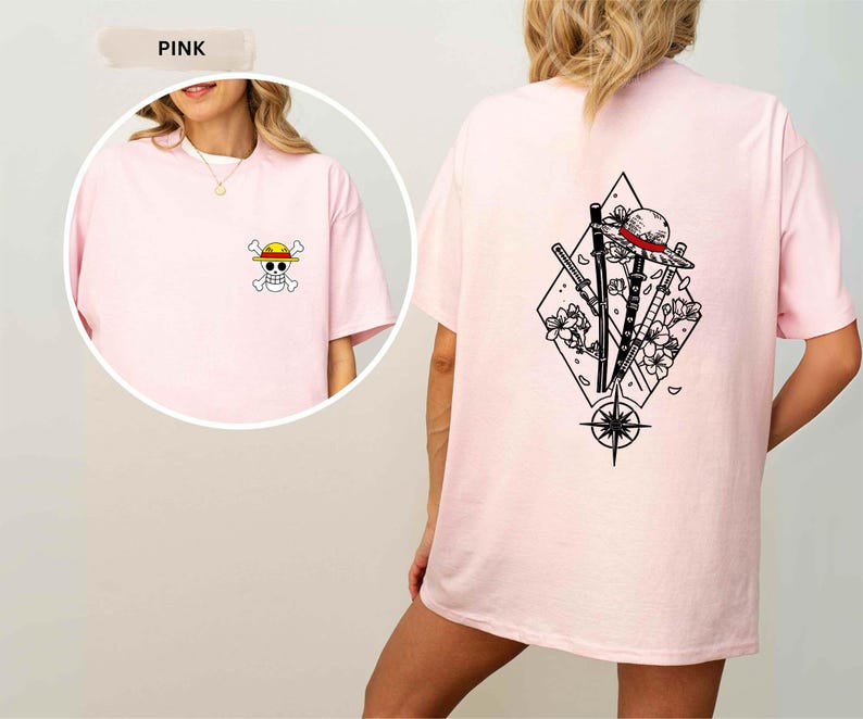 May include: Pink t-shirt featuring a small cartoon skull and crossbones with a straw hat on the front. The back of the shirt displays a black and white graphic of a straw hat, swords, flowers, and a compass within a diamond shape.