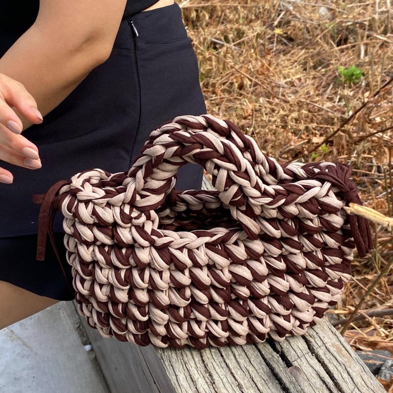 Puede incluir: Bolso tote tejido a mano en marr&oacute;n y beige. El bolso presenta un asa resistente y un dise&ntilde;o trenzado texturizado. Fabricado con un material suave y flexible, es adecuado para transportar varios objetos.