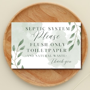 May include: A rectangular sign with the text "SEPTIC SYSTEM Please FLUSH ONLY TOILETPAPER .AND NATURAL WASTE. Thank you" in black script and sans-serif fonts. The sign has a watercolor background with green leaves and is set on a wooden plate.