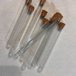 May include: A group of clear glass test tubes, each sealed with a cork stopper. The tubes are positioned at different angles, highlighting their transparency. The corks are a natural brown, providing a contrast to the clear glass. Suitable for scientific or decorative purposes.