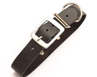 May include: A black leather dog collar with a silver-colored buckle and a D-ring. The collar is made of a single strip of leather and has two rivets near the buckle. The buckle is square and has a single prong.