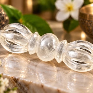 Peut inclure: Un vajra en cristal de quartz transparent et translucide, doté d'une poignée sphérique centrale flanquée de deux extrémités symétriques en forme de cage à plusieurs branches. L'objet présente une surface lisse et polie.
