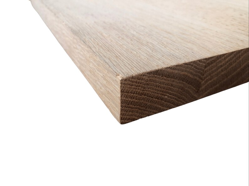 May include: Close-up of the edge of a light brown wooden board. The grain of the wood is visible.