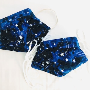 May include: Two blue fabric face masks with a white star pattern. The masks are tied together with white string.