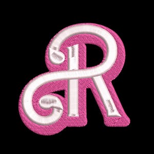 以下が含まれることがあります： スタイリッシュなフォントで刺繍された白い文字「R」が施されたピンクの布製パッチ
