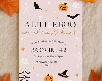 May include: A pink Halloween-themed baby shower invitation with the text "A Little Boo is almost due!" and "Babygirl #2". The invitation features illustrations of a black cat, pumpkins, bats, ghosts, and stars. Autumn leaves and a pumpkin are in the background.