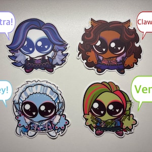 Op de afbeelding: Vier chibi-stijl karakterstickers met grote ogen en hartvormige reflecties. Links boven een figuur met paars haar en een tekstballon "Spectra!". Rechts boven bruin haar en "Clawdeen!". Links onder blauw haar en "Abbey!". Rechts onder groen haar en "Venus!".