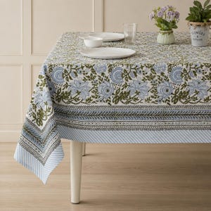 Peut inclure: Une nappe rectangulaire ornée d'un motif floral imprimé au bloc dans des tons bleu clair et vert olive sur fond blanc. Le design comprend une large bordure avec un motif de feuilles répétitif et un bord rayé fin le long de l'ourlet.