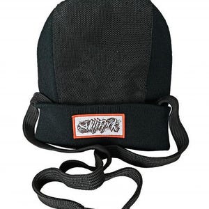 Puede incluir: Gorro negro con una parte superior de malla y una banda de punto. El sombrero presenta un parche rectangular con texto blanco y un borde naranja. Un grueso cordón negro está unido al sombrero.