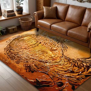 May include: An abstract rug in shades of orange, brown, and gold. The rug features a textured design resembling a stylized face or portrait. The rug is placed on a wooden floor, with a leather sofa and window in the background.