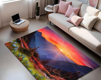 Op de afbeelding: Een rechthoekig vloerkleed met een berglandschapontwerp bij zonsondergang. Het kleed toont een kleurengradatie van rood, oranje, blauw en groen, met een gedetailleerde weergave van bergen, bomen en bloemen. Het kleed is geplaatst in een woonkamer.