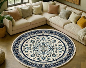 Puede incluir: Una alfombra redonda con un fondo crema y un detallado diseño floral azul. La alfombra tiene un borde azul oscuro y está colocada sobre un suelo de madera frente a un sofá seccional beige.