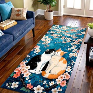 May include: A rectangular rug featuring a pair of cats nestled together amidst a floral design. One cat is black and white, the other is orange and white. The rug has a teal background with white and pink flowers.