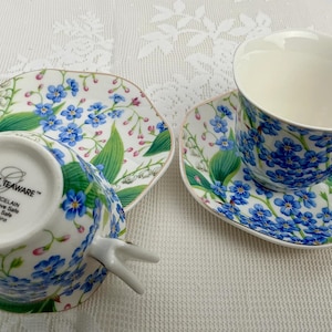 May include: A white ceramic mug with a black handle and the text "But First, Coffee" in a bold, black font. The mug sits on a white surface, showcasing its clean design.