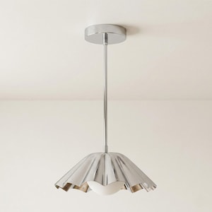 May include: A modern, chrome-finished pendant light fixture. The light features a fluted, umbrella-shaped shade and a spherical, frosted glass globe. The fixture is suspended from a circular ceiling mount by a slender, straight rod.