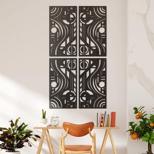Könnte beinhalten: Vierteilige schwarze Wandkunst mit einem abstrakten geometrischen Design. Das Kunstwerk ist an einer weißen Wand über einem Holztisch mit einem Lederstuhl angebracht. Eine Topfpflanze und ein kleiner Orangenbaum befinden sich ebenfalls im Raum.