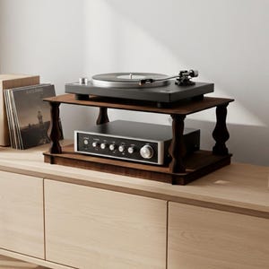 May include: A modern entertainment setup featuring a turntable on a dark wood stand, a silver stereo receiver, and a wooden speaker. The setup is placed on a light wood cabinet, creating a minimalist aesthetic.
