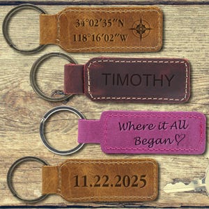 May include: Four leather keychains in various colors, each with a metal ring. One keychain has coordinates and a compass rose, another reads "TIMOTHY", a third says "Where it All Began", and the last displays the date 11.22.2025.