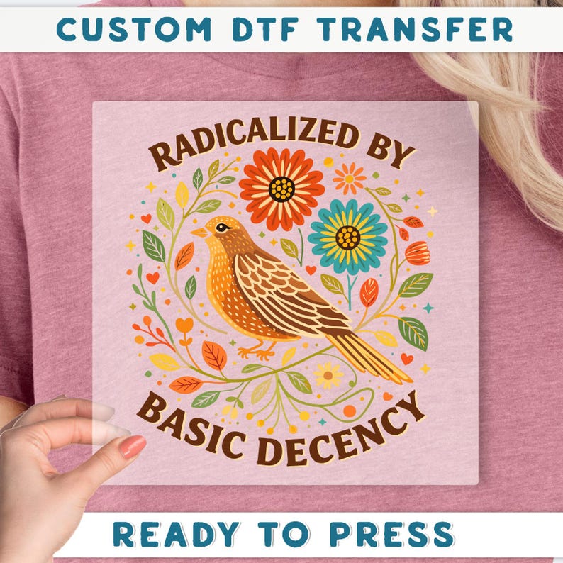 a hand holding a transparent square with a colorful illustration of a bird surrounded by flowers and leaves.