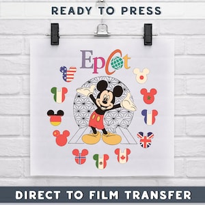May include: A white sheet with a Mickey Mouse design, the word "Epcot", and the text "Ready to Press" and "Direct to Film Transfer". The design features Mickey Mouse with his arms open, surrounded by Mickey Mouse-shaped flags.