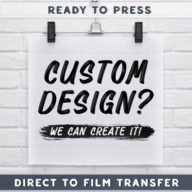 The image is a poster with the text "CUSTOM DESIGN? WE CAN CREATE IT!" displayed prominently. The poster is hanging on a wall, and there is a sign that says "READY TO PRESS" at the top. The image also includes the text "DIRECT TO FILM TRANSFER" at the bottom.
