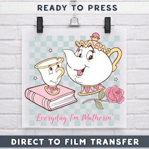 May include: A direct-to-film transfer featuring a cartoon illustration of a teapot, teacup, book, and rose. The text "Everyday I'm Motherin'" is displayed in pink. The background is a light blue and white checkered pattern.