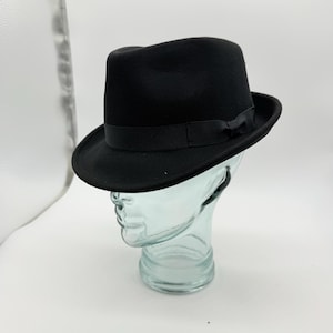 Cappello classico trilby in feltro di lana nero, alto circa 11 cm e con tesa di 5 cm.