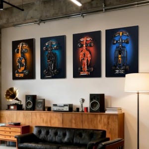 May include: Four framed canvas prints of Formula 1 race cars. Each print features a different car design, with orange, black, and red color schemes. The cars are set against a dark background with colored spotlights.