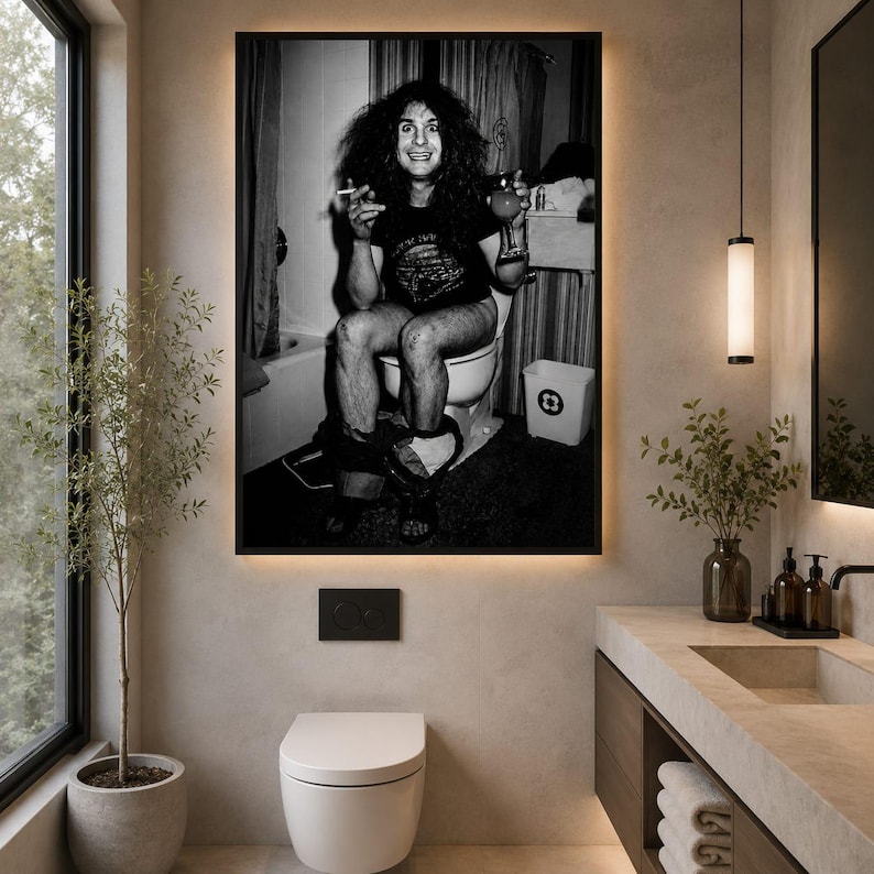 May include: A black and white wall art print featuring a person with long dark hair sitting on a toilet, holding a cigarette in one hand and a glass in the other. The person wears a dark t-shirt and is positioned in a bathroom setting with a shower curtain and a waste bin visible in the background.