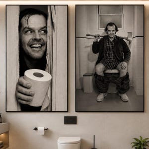 May include: Two black and white wall art prints. The left print shows a man peering through a broken wooden door holding a roll of toilet paper. The right print shows the same man sitting on a toilet holding an axe over his shoulders.